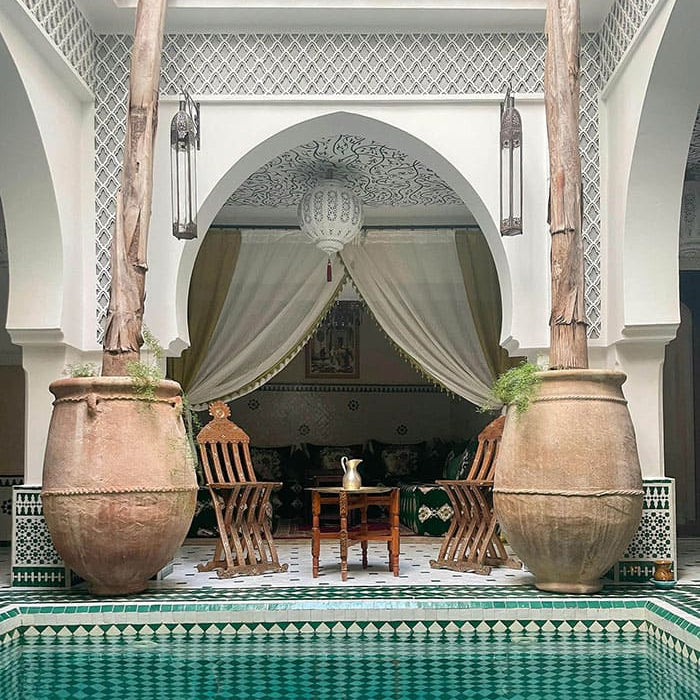 Cour intérieure avec piscine, pots en terre cuite et rideaux blancs