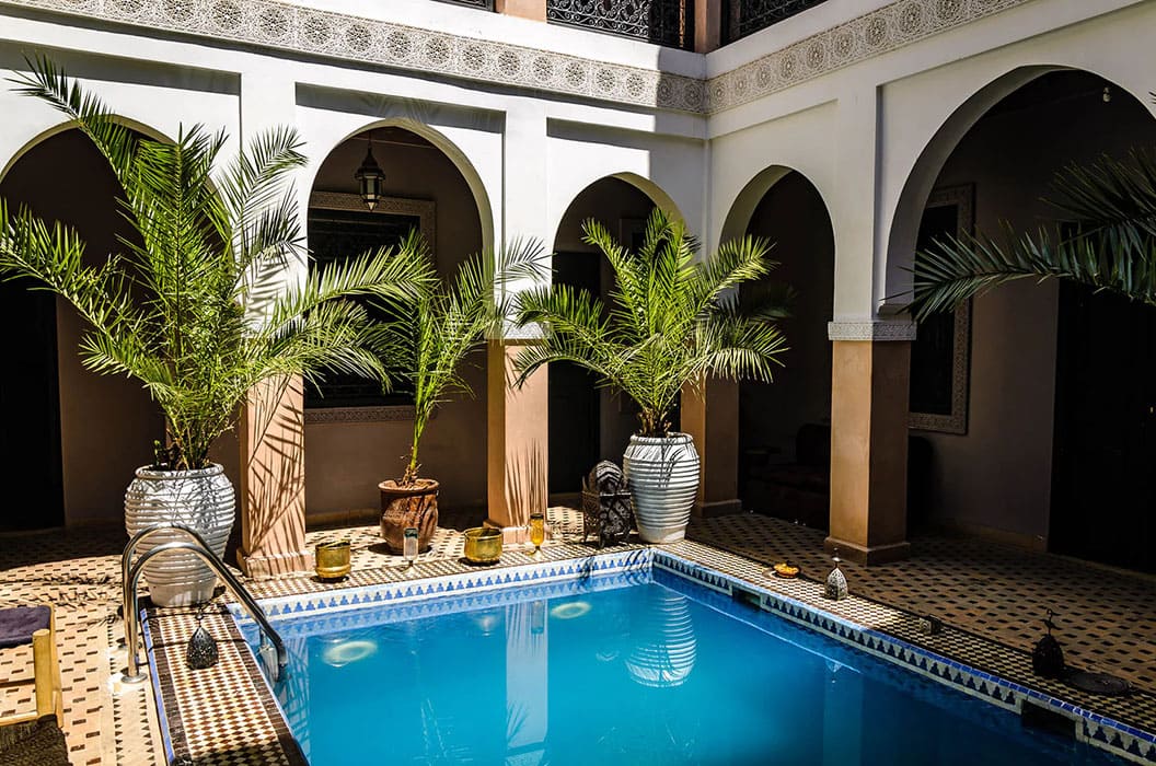 Piscine intérieure entourée de palmiers et de colonnes marocaines