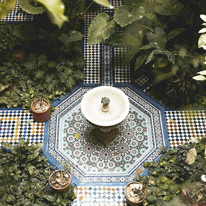 Fontaine centrale dans un jardin marocain avec mosaïques et plantes