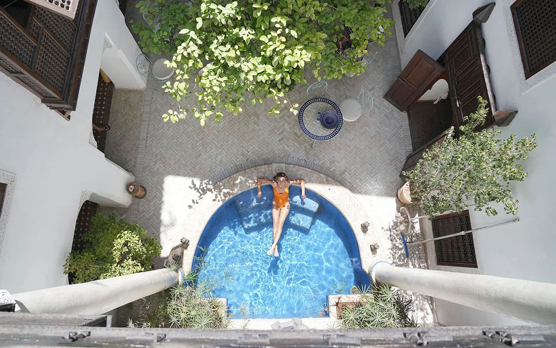 Cour intérieure avec piscine, arbre central et personne dans la piscine