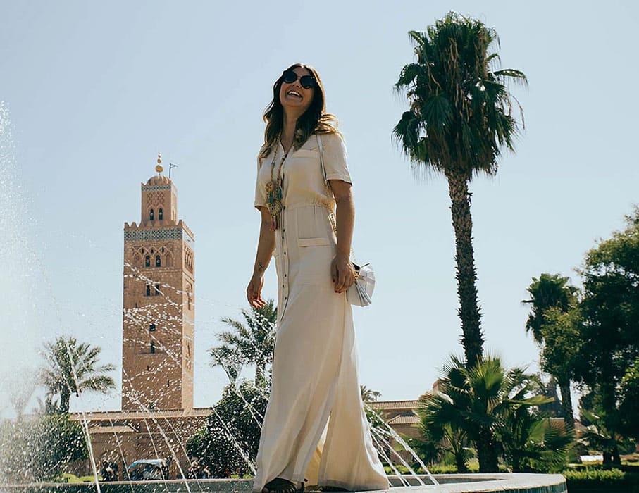 Femme souriante devant une fontaine et un minaret