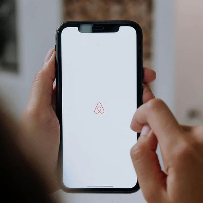  Personne utilisant l'application Airbnb sur un smartphone