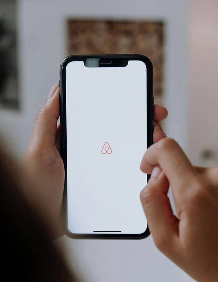  Personne utilisant l'application Airbnb sur un smartphone