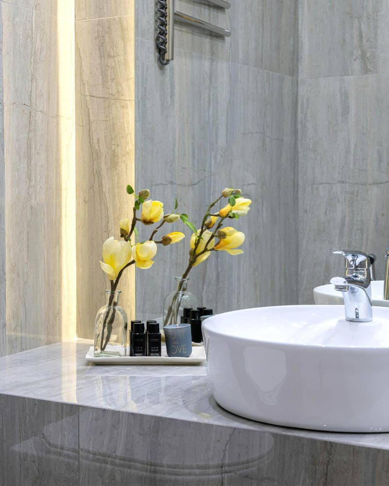 Salle de bain moderne avec lavabo rond, fleurs jaunes et accessoires