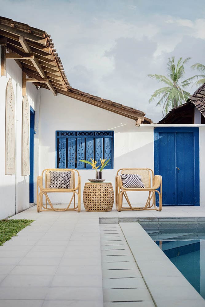 Terrasse avec chaises en rotin et table d'appoint près de la piscine