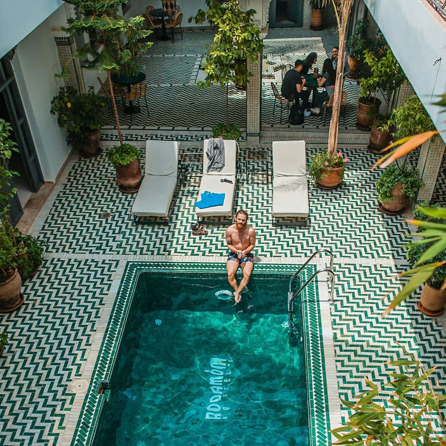 Homme assis au bord d'une piscine d'un riad