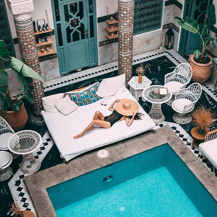 Femme qui bronze au bord de la piscine dans un riad marocain