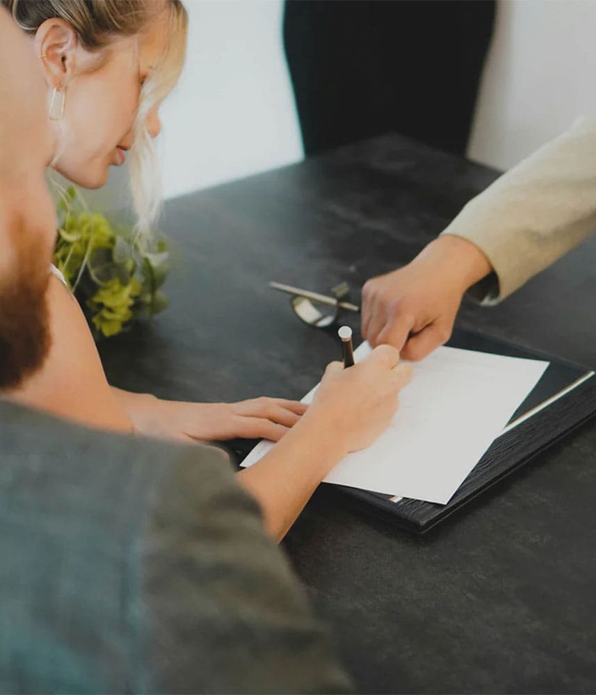 Femme signant un document avec deux personnes