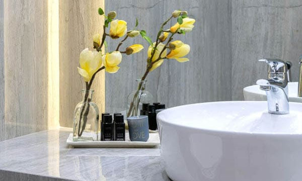 Salle de bain moderne avec lavabo rond, fleurs jaunes et accessoires