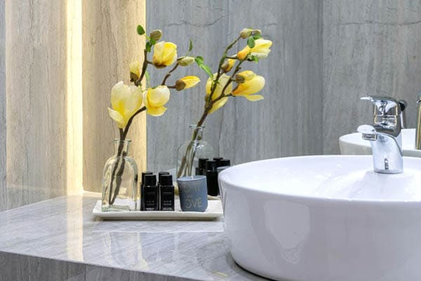 Salle de bain moderne avec lavabo rond, fleurs jaunes et accessoires