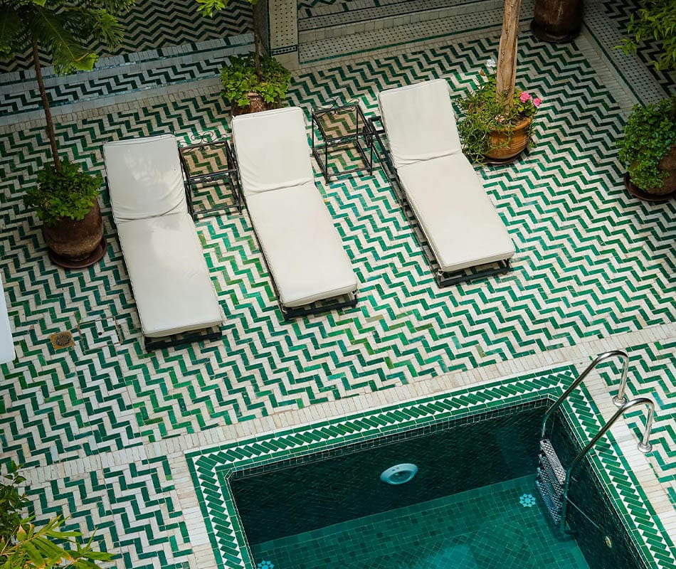 Piscine avec transats et carrelage en mosaïque verte dans un patio