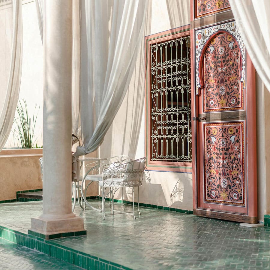 Terrasse avec portes marocaines décorées, rideaux blancs