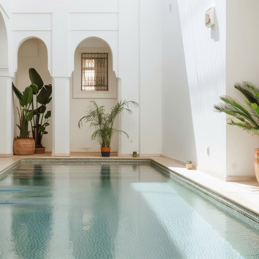 Piscine intérieure avec arches blanches et plantes en pot